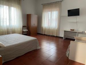 a bedroom with a bed and a desk and a television at The River in Fordongianus +6 photos