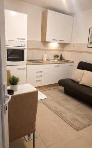 a kitchen with white cabinets and a black couch at Apartman CannaVis in Split