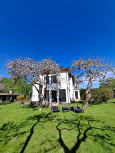 a house with a tree and chairs in the yard at Cozy Garden Villa in Ventspils