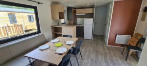 a dining room with a table and a kitchen at Camping 3 étoiles - Piscine - ccbgbi0 in Lavelanet