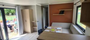 a living room with a table and a room with people at Camping 3 étoiles - Piscine - ccbgbi0 in Lavelanet