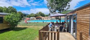 a group of people sitting at a table by a pool at Camping 3 étoiles - Piscine - ccbgbi0 in Lavelanet +15 photos
