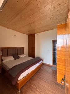 a bedroom with a bed with a wooden ceiling at Forest Breeze Homestay in Kanatal