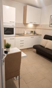 a kitchen with white cabinets and a black couch at Apartman CannaVis in Split