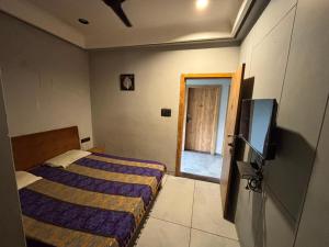 a bedroom with a bed and a flat screen tv at Shree Hariraj Guest House in Vapi