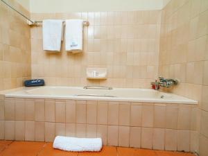 a bath tub in a tiled bathroom with towels at Emoyeni Guest House in Nelspruit +40 photos