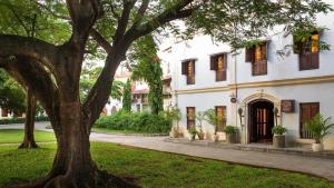 a large white house with a tree in the yard at Beyt Al Salaam in Zanzibar City