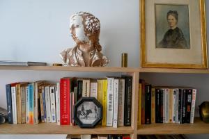 a book shelf with books and a statue on it at Château de Saint Clair in Saint-Clair-sur-lʼElle