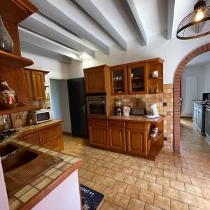 a large kitchen with wooden cabinets and appliances at Gîte chez PAT in Ychoux