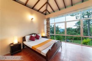 a bedroom with a bed and a large window at The Montfort - Kandy in Kandy
