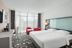 a hotel room with a large white bed and a desk at Park Inn by Radisson Sarvar Resort & Spa - All Inclusive in Sárvár