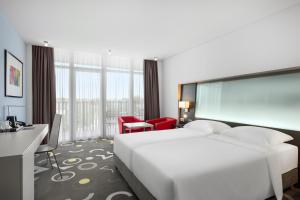 a hotel room with a large white bed and a desk at Park Inn by Radisson Sarvar Resort & Spa - All Inclusive in Sárvár