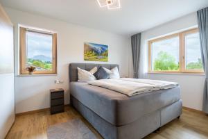 a bedroom with a large bed with two windows at FeWo Iller im Allgäu in Sonthofen +20 photos