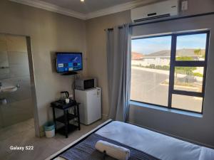 a bedroom with a bed and a television and a window at Pado B & B in Gqeberha