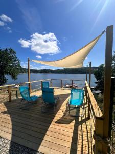 four chairs and a hammock on a deck next to the water at Osada Znamirowice in Znamirowice