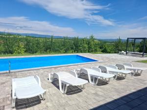 a group of white chairs and a swimming pool at Vikendica sa bazenom Staša in Banja Luka