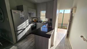 a small kitchen with a refrigerator and a window at La Palma villas 6 in Mossel Bay +8 photos