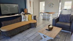 a living room with a couch and a tv and a table at La Palma villas 6 in Mossel Bay