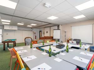 a classroom with tables and chairs and a whiteboard at greet Hotel Bordeaux Aeroport in Mérignac