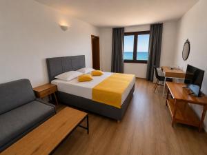 a bedroom with a bed and a couch and a desk at Palma Beach Hotel in Kranevo