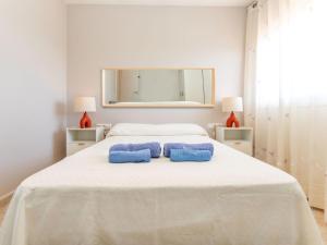 a white bedroom with two blue towels on a bed at Holiday Home Panoramic by Interhome in Tordera
