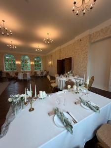 a dining room with tables with white tablecloths at Viesnīca Meirānu Muiža in Meirāni