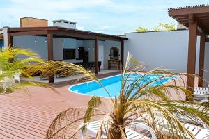 a patio with a swimming pool and a house at Condomínio Brises Downtown Garopaba in Garopaba