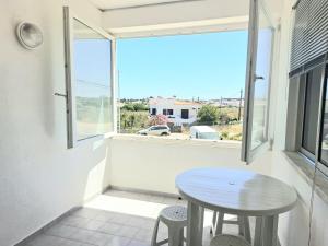 a small table and chairs in a room with a window at Beach&Surf Flat in Aljezur