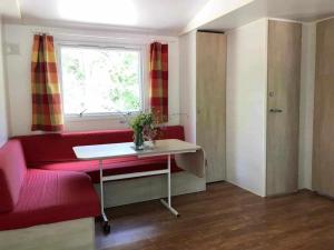 a living room with a red couch and a window at Camping 3 étoiles - Piscine - ccbgccf in Rennes-les-Bains