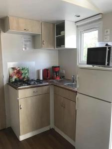 a small kitchen with a white refrigerator and a microwave at Camping 3 étoiles - Piscine - ccbgccf in Rennes-les-Bains