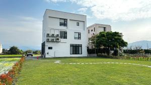 a white building with a grass field in front of it at 根本家民宿 in Dayi