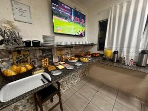 a breakfast table with food and a tv on the wall at Pousada Saturnino in Hortolândia