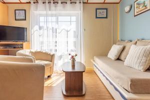 a living room with a couch and a table at Le Chalet 67, vue Lac Guerlédan & Accès Direct à l'Eau in Caurel