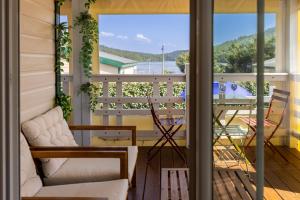 a porch with a couch and chairs on a balcony at Le Chalet 67, vue Lac Guerlédan & Accès Direct à l'Eau in Caurel