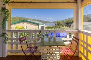 a porch with a table and chairs on a balcony at Le Chalet 67, vue Lac Guerlédan & Accès Direct à l'Eau in Caurel