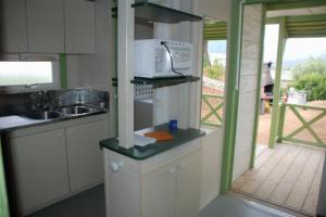 a small kitchen with a microwave and a sink at Camping 3 étoiles - Piscine - ccbfihb in Casaglione