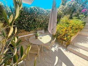 a patio with a table and chairs and an umbrella at Whitealcyone Fit & Zen Apartment in Artemida