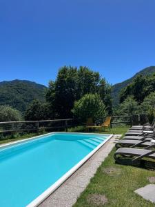 a swimming pool with lounge chairs and mountains in the background at Casa Europa in Ledro