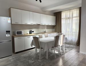 a kitchen with a table and white cabinets and a refrigerator at Коттедж в Азиа Палас in Chon-Sary-Oy