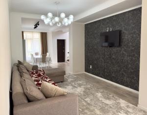 a living room with a couch and a tv on a wall at Коттедж в Азиа Палас in Chon-Sary-Oy
