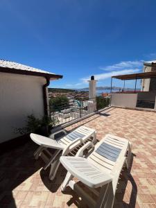 Ein Paar weiße Stühle und Tische auf einer Terrasse in der Unterkunft Guesthouse Donko 1 & 2 in Senj