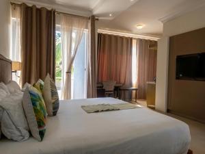 a bedroom with a large white bed with a large window at Cycad Palm Hotel in Gaborone