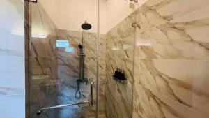 a bathroom with a shower with a glass door at Safari Lodge Tempstay in Nochchiyagama