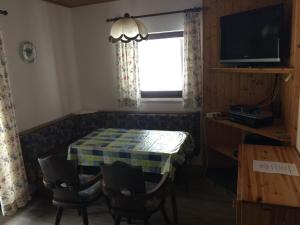 a room with a table and chairs and a television at Haus Serena in Sonnenalpe Nassfeld