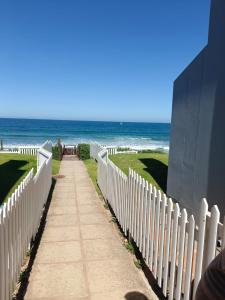 a white picket fence with the beach in the background at La Palma villas 6 in Mossel Bay