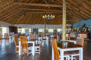 a restaurant with wooden tables and chairs and a ceiling at Gondwana Hakusembe River Lodge in Rundu