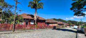 a red house with a fence and a palm tree at Hospedagem Maranata in Santo André