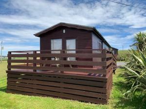 a small house with a wooden fence around it at Amazing Sunsets and Sea Views - Lodge Cabin Farm Stay - Caol Ila - Lodge 8 in Stranraer