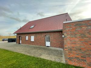 a brick house with a red roof and a driveway at Am Wangermeer 38 in Wangerland