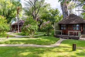 a cabin in a park with a grass yard at Gondwana Hakusembe River Lodge in Rundu
